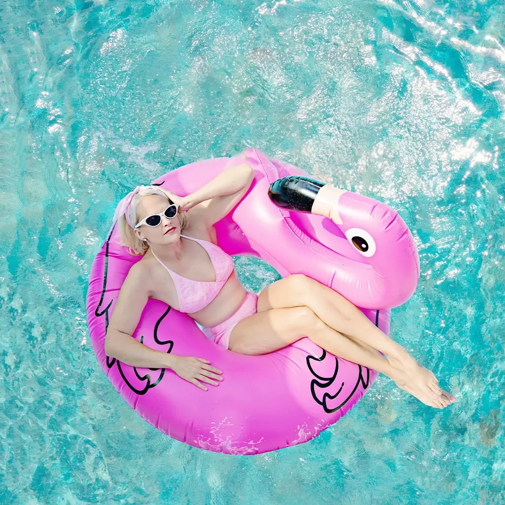 A young woman sits in a flamingo pool floatie in the middle of a new fiberglass pool.